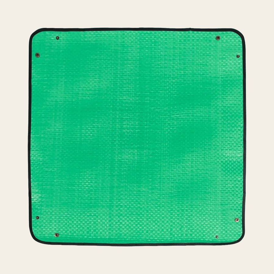 The green mat lying flat, showing its black binding and corner press studs